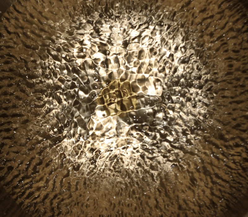 Lichtreflexionen auf Wasser in einer Klangschale